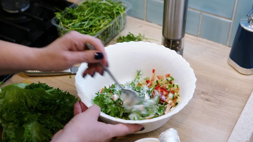 Vegetable fresh salad. Woman cooking a Green salad with cucumbers, onion, lettuce, pepper and tomatoes. preparation. Wooden kitchen worktop, top view. Healthy diet. Organic food concept. Close up
