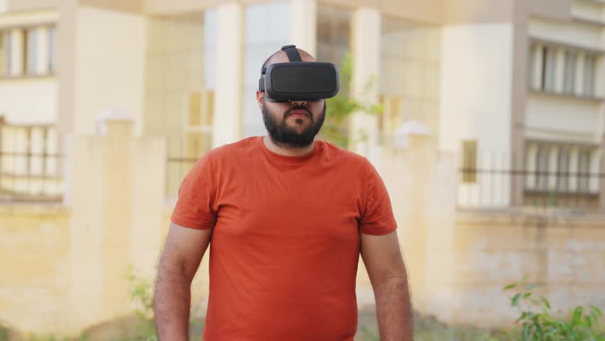 Bald indian Man Removing VR Headset and Smiling at Camera