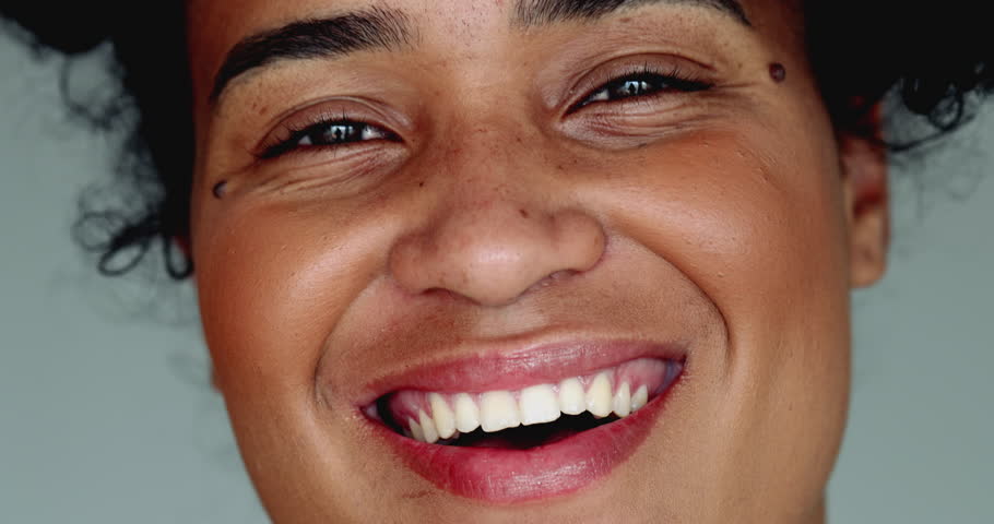 One happy young black Brazilian woman of African descent smiling at camera in tight macro close-up facial detail smile with friendly demeanor