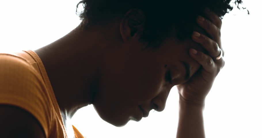 Candid Lonely Young Woman Struggling with Depression – Pensive Profile Close-Up of Person Holding Head in Hand, Suffering Emotional Pain in dramatic silhouette