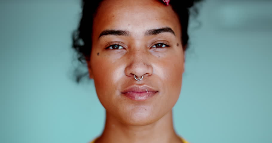 One young black latina woman looking at camera with neutral expression. Female 20s South American person of African descent close-up face
