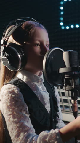 Girl during vocal lesson in recording studio. Young girl student with loose hair practices tones for good sound. Audition before taking part in talent show