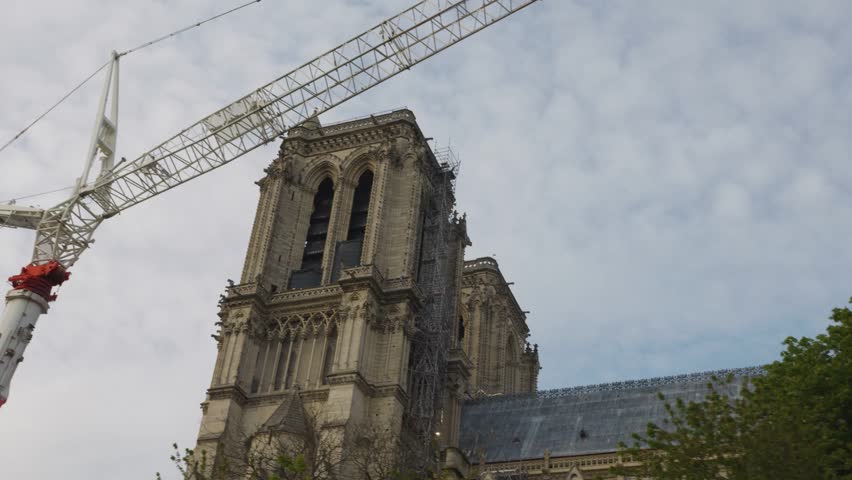 Riverboat cruise on the Seine. View of the Isle of Cite, Notre-Dame de Paris, cranes during the reconstruction of the cathedral after the fire and the arch bridge the Pont de l'Archeveche. 