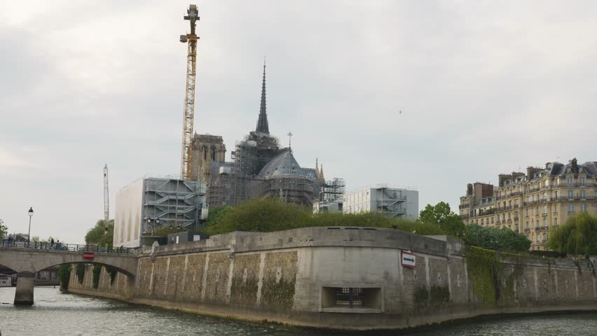 Riverboat cruise on the Seine. View of the Seine River, island de Cite, Notre-Dame de Paris, and two bridges, the Arch bridge the Pont de l'Archeveche and the Steel beam bridge the pont Saint-Louis.
