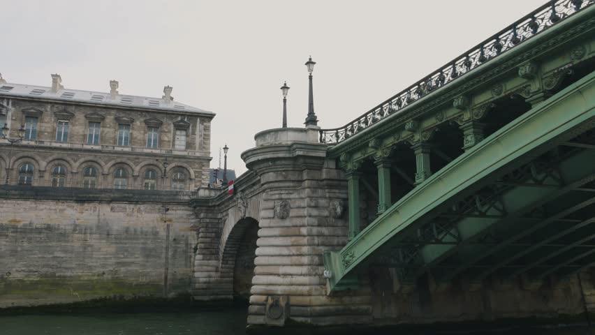 Riverboat cruise on the Seine. A boat sails under the green metal structures of the Pont Notre-Dame bridge over the Seine River, Paris, France. View of the Seine River, bridge and embankment.