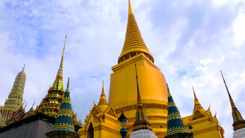 A dramatic view from below of the Grand Palace in Bangkok, showing its towering spires and intricate architectural details.