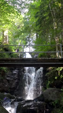 A woman on the upper part of a wooden bridge at the Todtnau waterfall in the Black Forest in Germany