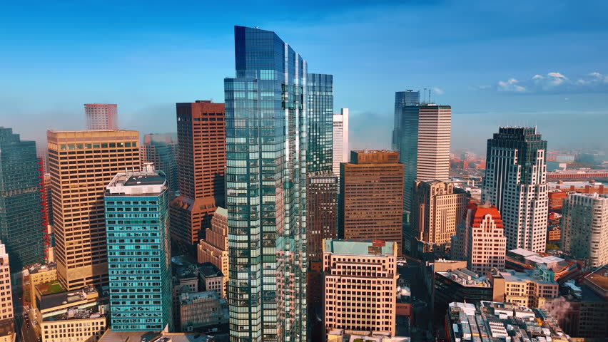 Approaching the high-rise tower of glass and metal. Thick fog covers the horizon. Boston, Massachusetts, USA. Aerial view.