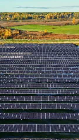 Solar field under sunset glow highlighting rows of panels and darkening terrain lines, even texture, aerial tracking left