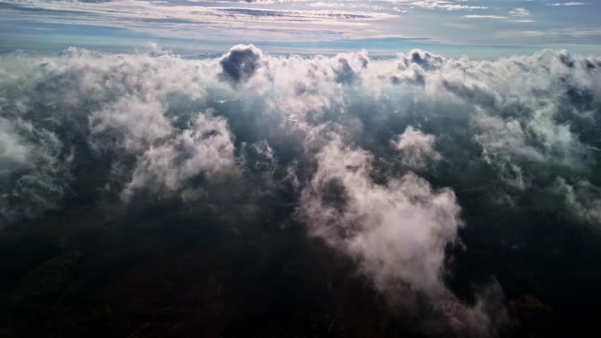 Soft, billowy clouds floating above a lush green landscape in a serene, peaceful scene