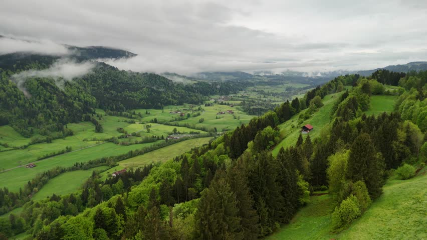 Cloudy mountain view with pine trees and alpine houses in Austria