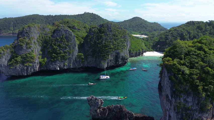 Tourism in Thailand. Phi Phi Islands, many tourists on boats are engaged in sailing on vacation in Thailand. Boat tourism from Phuket. Limestone cliffs and clear sea water near the coast.
