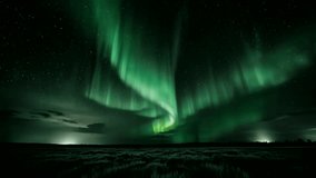 The Northern Lights stretch across the horizon in a mesmerizing display, casting an ethereal glow over the seemingly flat terrain and distant settlements. - Powered by Shutterstock - Get 15% off with code: PIKWIZARD15