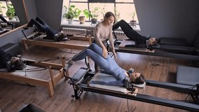 A group of woman exercises Glute bridge on a reformer bed machine in natural sunlight, focusing on pelvis and hips. - Powered by Shutterstock - Get 15% off with code: PIKWIZARD15