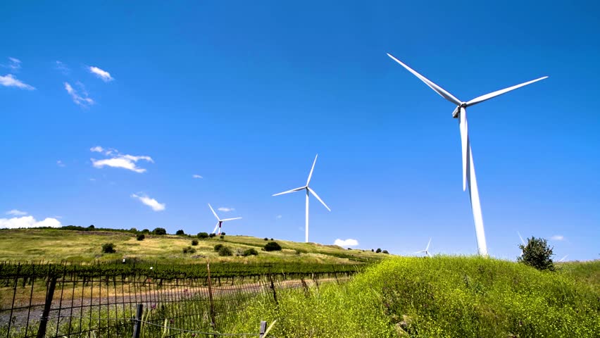 Wind farm in a rural area with a small vineyard against a dark blue sky; video shot in northern Israel