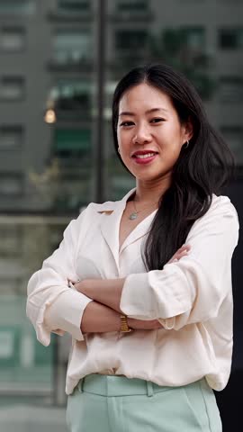 Young asian business woman crossing arms outside office building in the corporate city