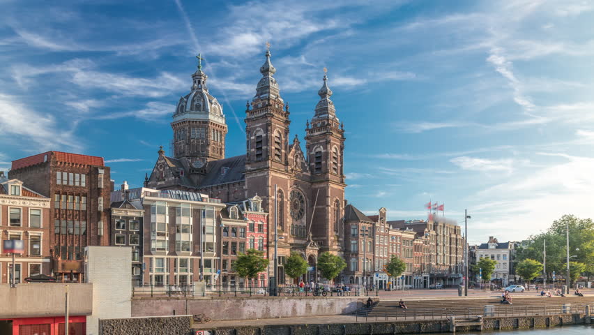 Hyperlapse of the Basilica of Saint Nicholas in Amsterdam's Old Centre near the Central Station. People walking along the waterfront by the boat station timelapse. Amsterdam, Netherlands
