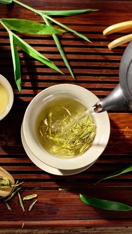 Pouring hot tea into tea cup on table, top view.
