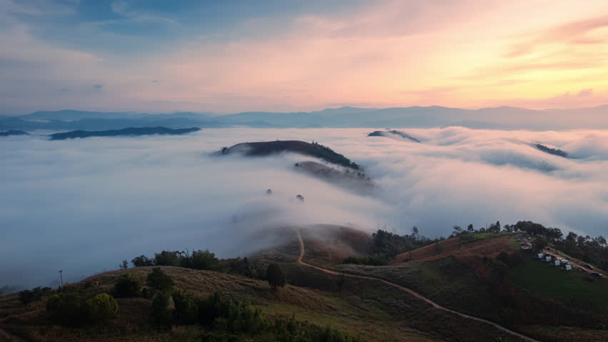 Hyperlapse aerial view of beautiful sunrise over sea of fog flowing over deforested mountain during harvest in countryside at Mae Jam, Chiang Mai, Thailand