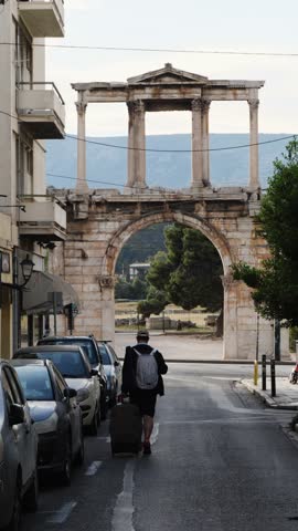 Tourist man with backpack and suitcase walks toward Hadrian