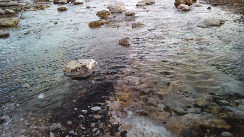 Close up of a small stream of hot boiling water, coming from the Geysir and Strokkur geysers in Iceland. The water flows down towards the camera