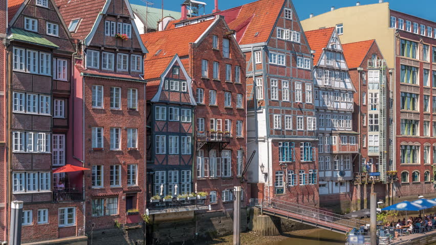 Aerial timelapse of Kleines Dock along the northern Elbe Canal in Hamburg, Germany. Picturesque cafes and historic brick houses line the serene waterfront, perfect for dining or enjoying tidal views