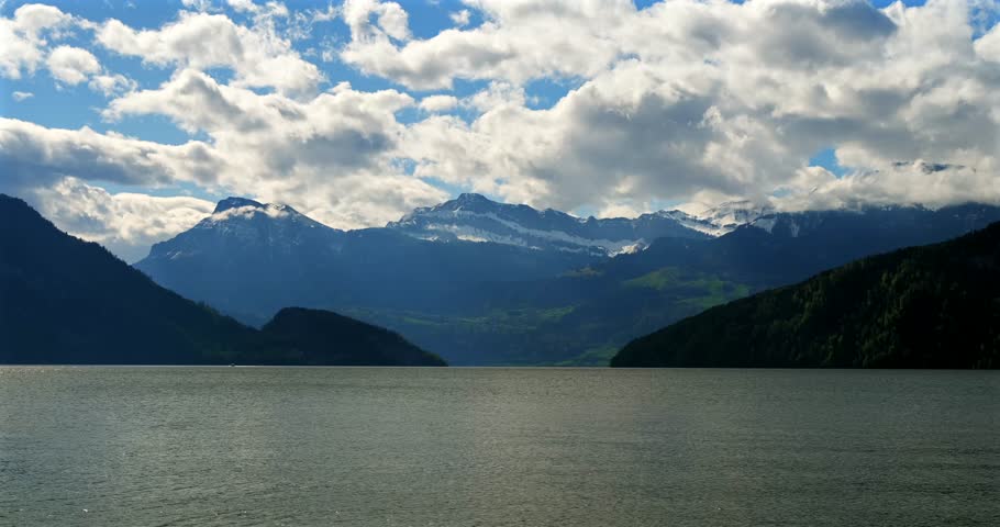 Majestic mountains reflected in calm lake under cloudy sky in Switzerland during late afternoon