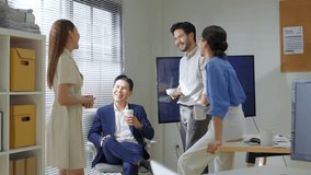Casual Asian business conversation in modern office, with people standing, sitting, and sipping coffee, enjoying a relaxed team interaction and collaborative workspace friendly teamwork in office - Powered by Shutterstock - Get 15% off with code: PIKWIZARD15
