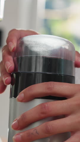 Woman opens coffee grinder in kitchen closeup. Lady uses modern domestic appliance for energetic beverage making at home. Easy and fast cooking
