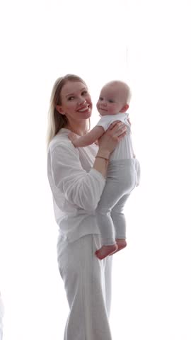 Mother and daughter. Happy smiling blonde mom hugging Little baby at home in front of white background with copy space, love, tenderness, motherhood and family connection