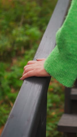 Woman holding onto staircase railing. Climbing up wooden steps to country house for rent to tourists. Active movement and walk in middle of forest