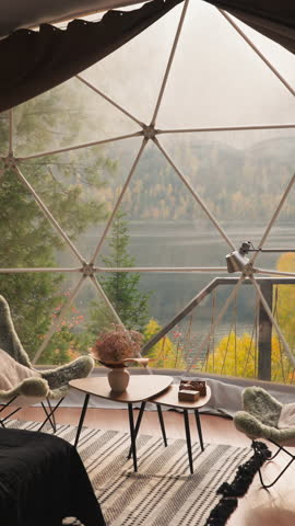 Modern glamping house with glass terrace. Relaxation place equipped with cozy furniture for lunch breaks to enjoy lake view. Glamping cottage for tourists