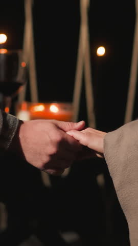 Man strokes woman hand closeup. Husband prepares romantic dinner for wife with wine in autumn evening during vacation. Candlelight dinner on terrace