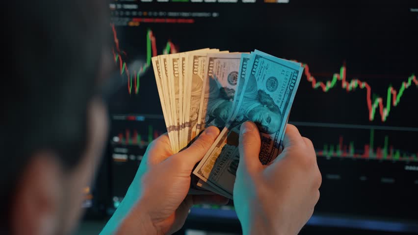 Trader Counting Dollars in Front of Charts