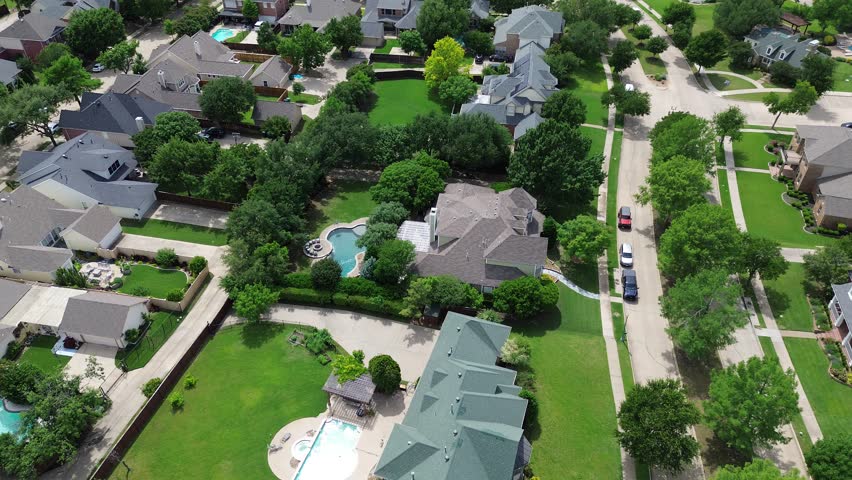 Large backyard of expensive two-story mansion homes with swimming pools in upscale neighborhood Carrollton, suburbs Dallas Fort Worth Metroplex, lush green treed lined residential street, flyover. USA