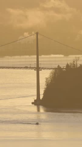 Cargo Ship and Tug Boat Pass Under Lions Gate Bridge in Vancouver, British Columbia at Golden Hour