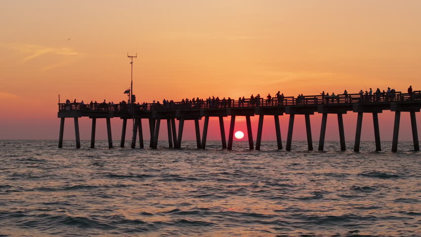 Venice, Florida. People enjoying bright sunset on fishing pier. Seaside summer activities on fresh air
