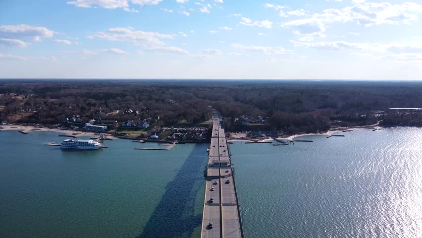 Aerial view of the Coleman Memorial Bridge stretching across the York River into Yorktown, Virginia, on a clear, sunny afternoon with light traffic and calm waters.