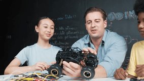 Smart teacher inspect car model construction to diverse student. high school children with mixed races listening mentor explain robotic model system at table with laptop and wires placed. Edification - Powered by Shutterstock - Get 15% off with code: PIKWIZARD15