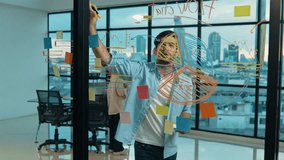 Professional businessman uses sticky notes at glass wall with graph to brainstorming idea while multicultural businesspeople discussing about marketing ideas at office with city view. Tracery - Powered by Shutterstock - Get 15% off with code: PIKWIZARD15