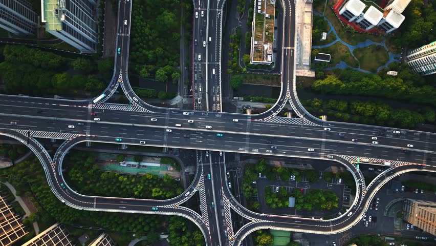 Aerial top down view of a busy junction reveals a multitude of vehicles traveling on various roadways. Hangzhou, China.