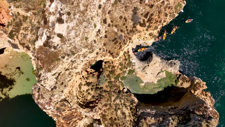 Aerial view of kayakers navigating turquoise waters near the dramatic sea cliffs and arches of Ponta da Piedade in Lagos, Portugal