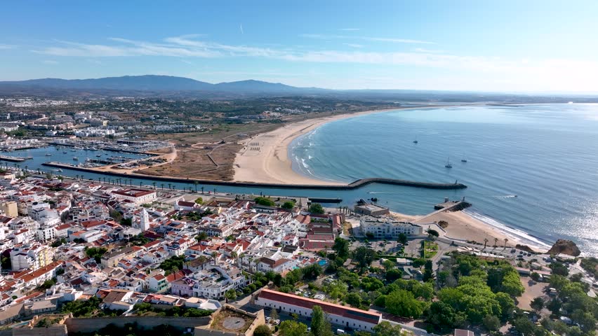 Wide aerial view of Lagos marina, town center, and expansive Meia Praia beach under clear skies