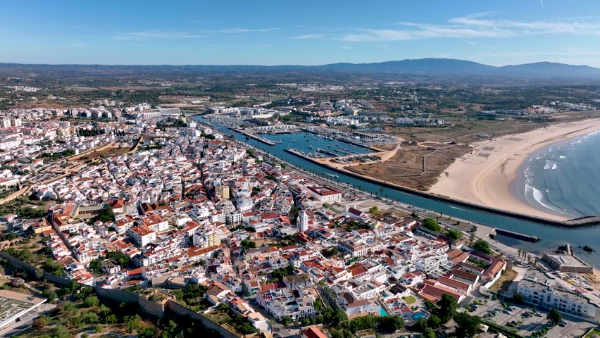 Wide aerial view of Lagos marina, town center, and expansive Meia Praia beach under clear skies