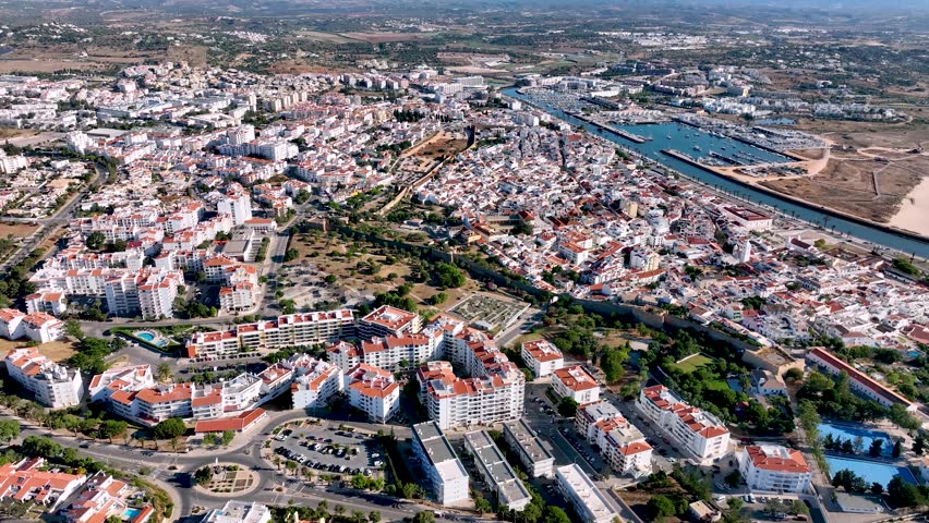 Aerial view of Lagos, Portugal, featuring its whitewashed buildings, red rooftops, historic old town, modern housing, marina, and surrounding countryside