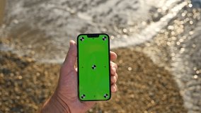 Mobile phone green screen mockup, man with smartphone at ocean beach, 4K with selective focus - Powered by Shutterstock - Get 15% off with code: PIKWIZARD15