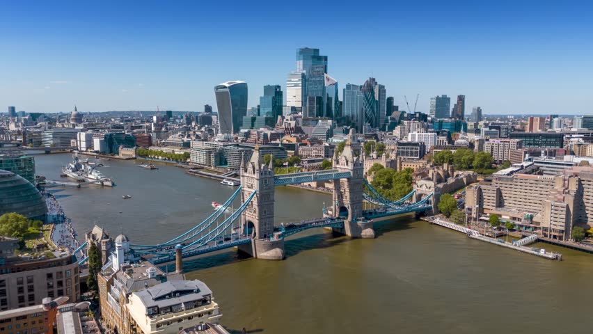 Aerial hyper time lapse view of the City and Tower Bridge in London, England, during a sunny summer day with river Thames boat traffic and people
