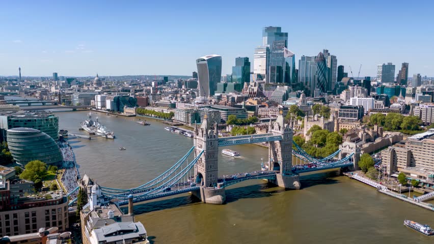 Aerial time lapse view of the City and Tower Bridge in London, England, during a sunny summer day with river boat traffic and people crowds