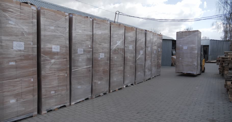 Forklift moving large wrapped pallet outdoors, Industrial packaging and storage logistics operation