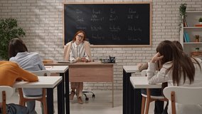 A teacher guides students in understanding grammatical tenses, providing explanations with examples. - Powered by Shutterstock - Get 15% off with code: PIKWIZARD15